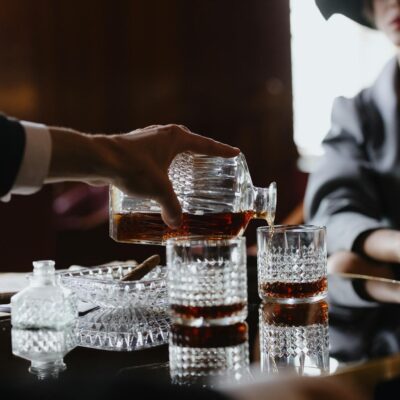 A sophisticated scene of whiskey being poured into crystal glasses on a reflective table in an elegant setting.