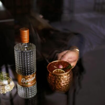 Close-up of a gin bottle and copper mug on glass table, perfect for cocktail enthusiasts.