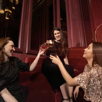 Three women enjoying a toast in a stylish, upscale indoor setting, celebrating friendship.