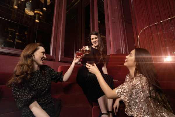 Three women enjoying a toast in a stylish, upscale indoor setting, celebrating friendship.